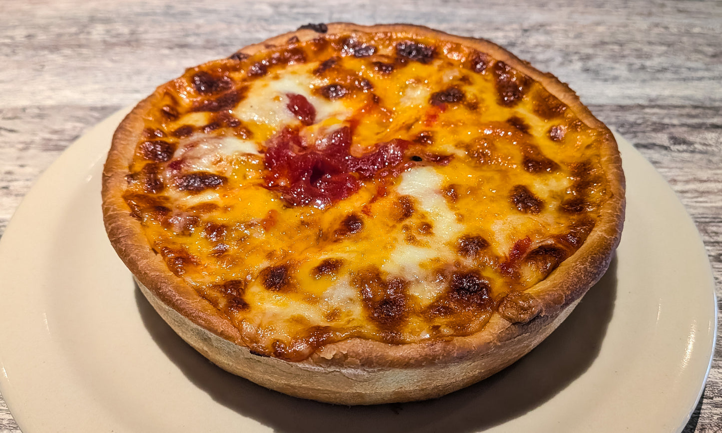 A Felix & Oscar's Cheese Topper pizza. The crust is topped with cheese, then toppings and sauce, then another layer of cheese on top.