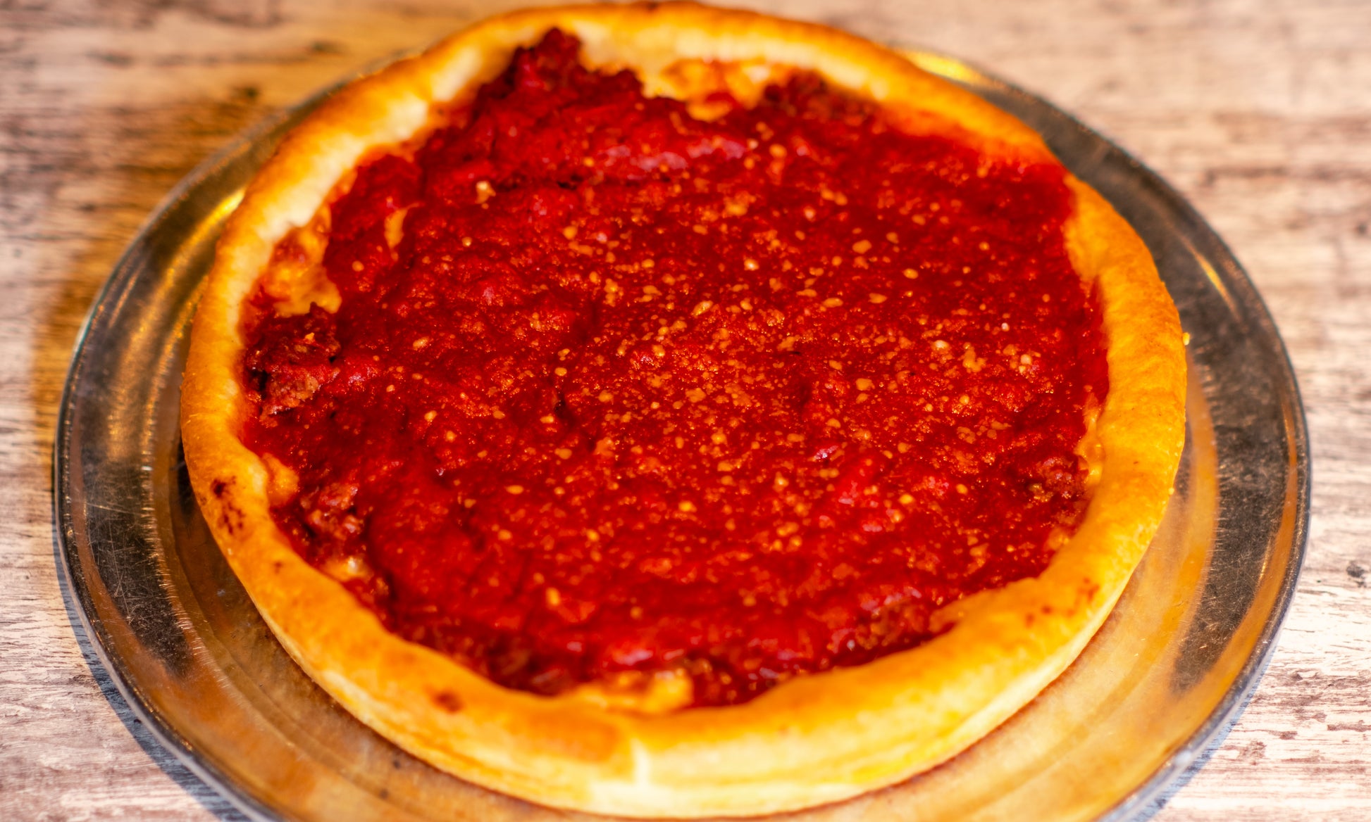 9-inch Chicago-style Deep Dish Grinder pizza with cheese on the bottom, topped with Italian grinder mix and sauce.